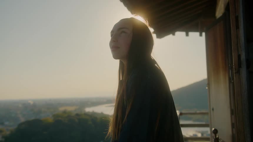 Early in the morning as the sun rise a woman stands in the balcony as she stares at the surrounding