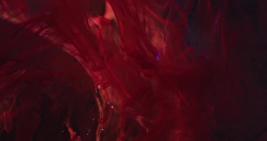 Strands of a red fluid are suspended within a clealy liquid