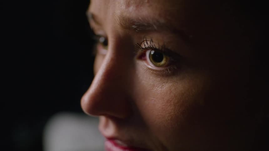 Woman with yellow tinted eyes looks up while frowning