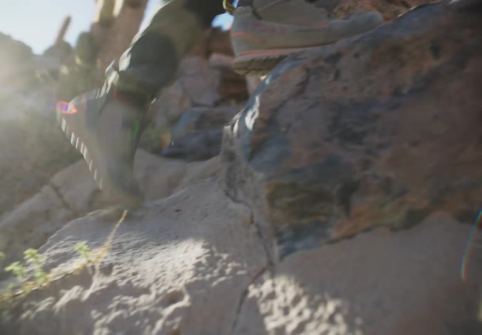 Closeup of a persons shoes climbing a rocky mountain during the day