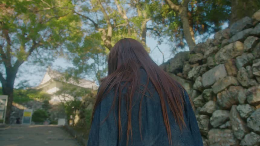A woman walking through the streets of a leafy neighborhood during the day