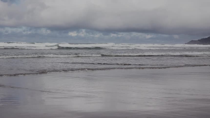 A beach with some waves and ripples going up to the shore