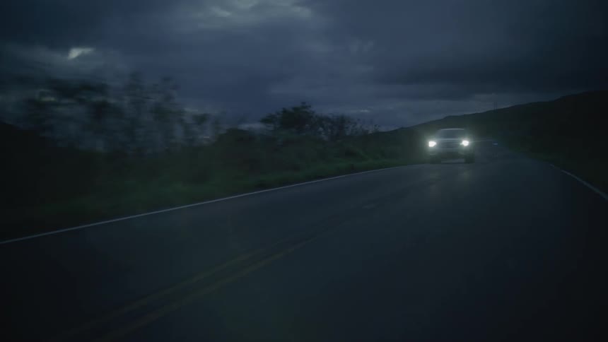 A car speeding down a deserted road at dusk