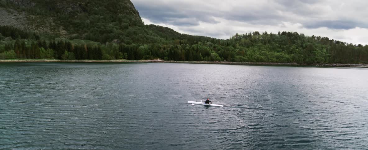 Solitary meditative row on open water surrounded by lush forests