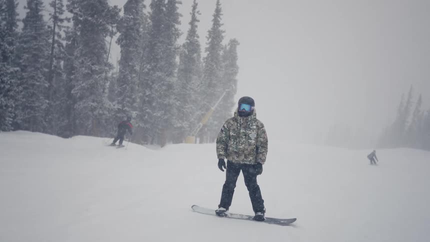 A man snowboarding slowly on snow during the day