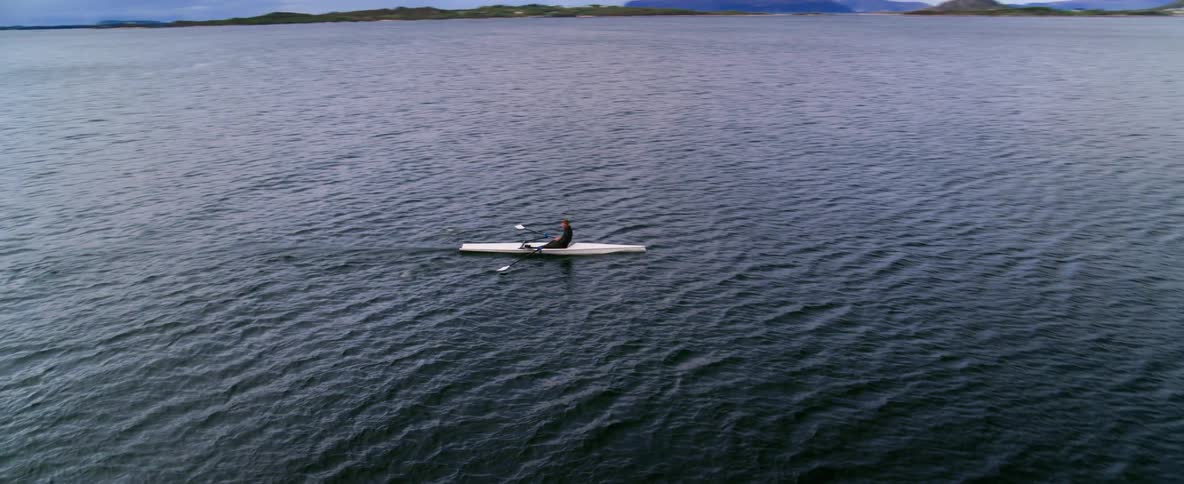 Dynamic camera movement showing a rowing athlete training on deep blue water