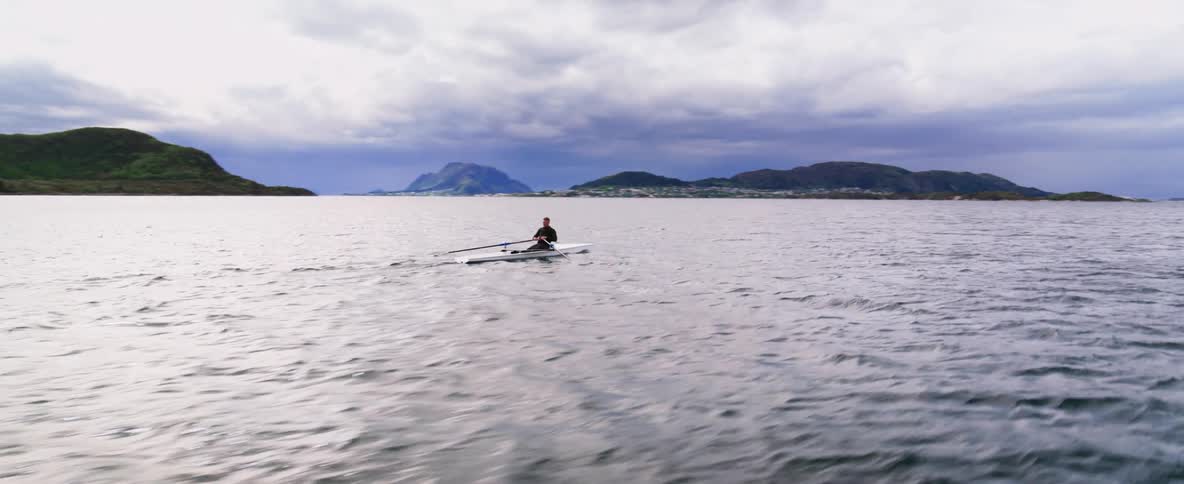 360 aerial of an athlete training in a boat on a vast expanse of water