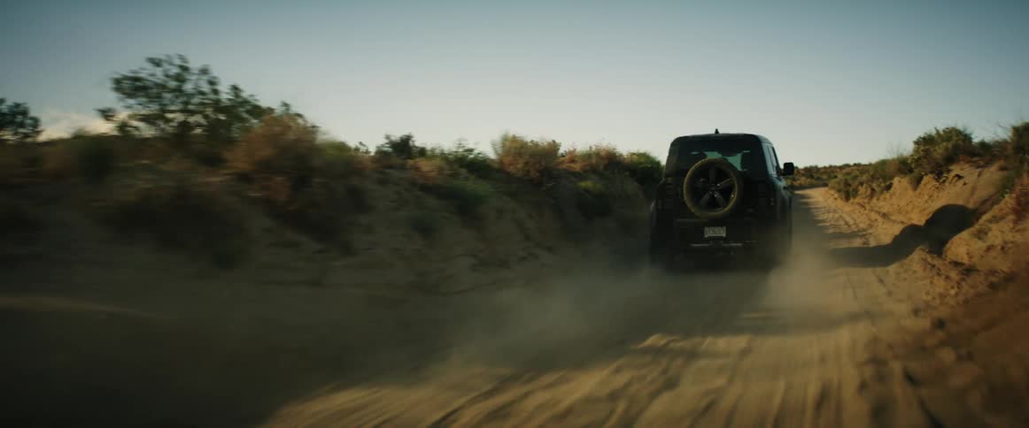 The truck leaves a dust cloud as it drives on the dirt road