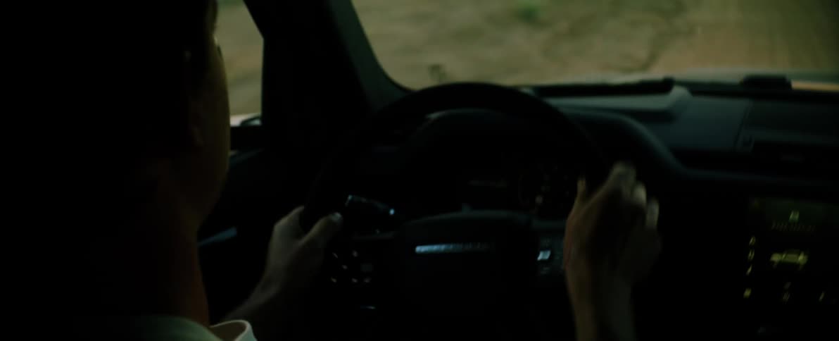 A man drives a car down a dirt road