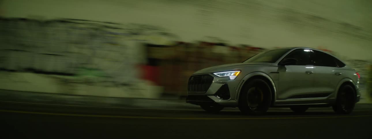 A car driving through a graffiti covered tunnel at night
