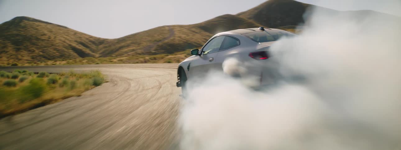 Sports car drives on desert road and burns rubber creating smoke
