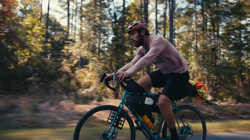 A man rides a bicycle through a forest