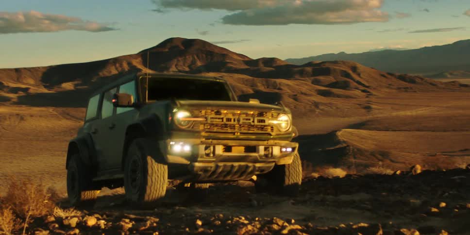 An offroad vehicle crossing desert terrain at sunset