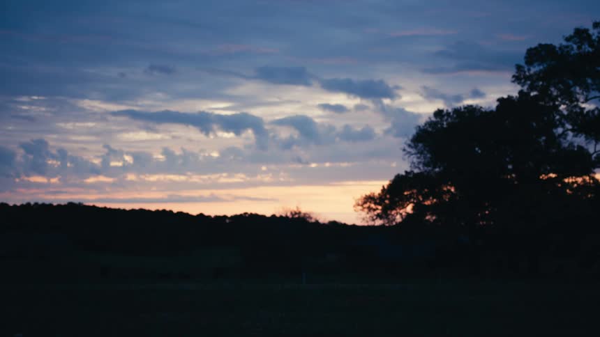 Cyclist rides down the road under a blue and pink sunrise