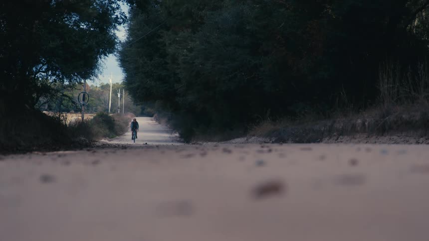 A person pedaling a bicycle on a rural road during the day