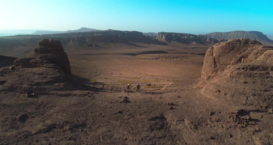Two people on mountain bikes and going down a hill in the middle of valleys