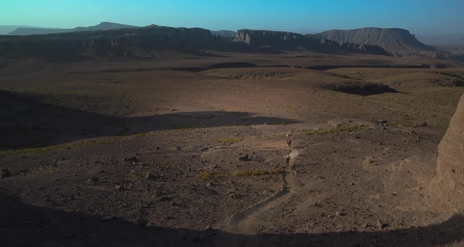Two people riding bicycles on a trail amidst an arid landscape