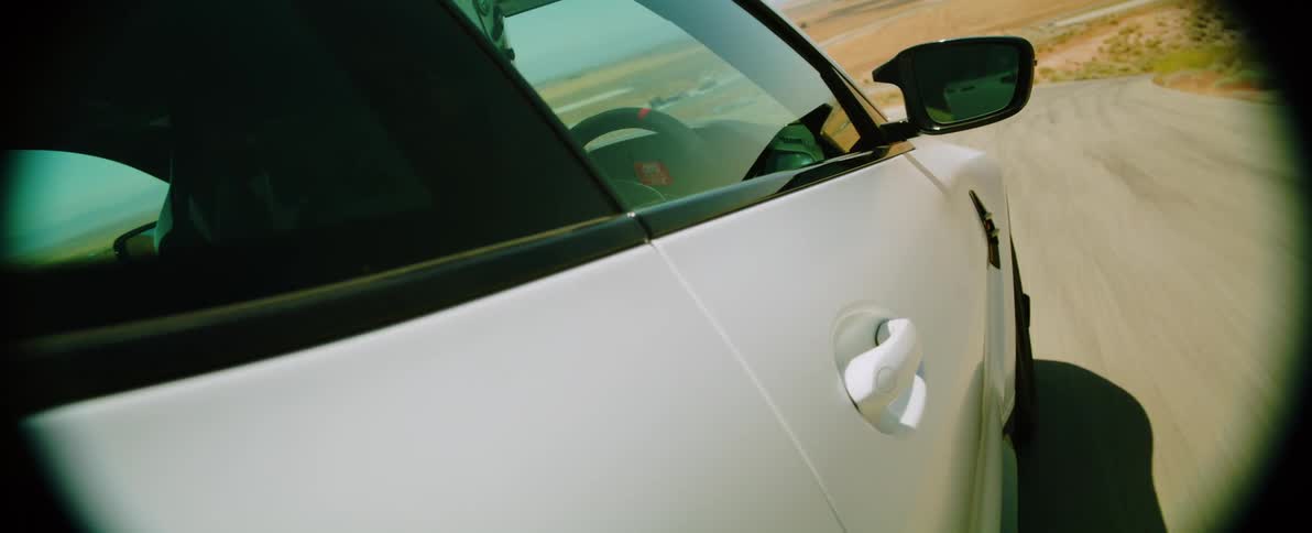 Close up of a white car driving on a dirt road