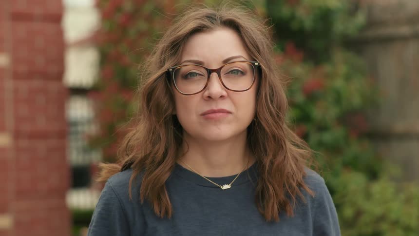 Close up of the face of a young woman with glasses and long hair
