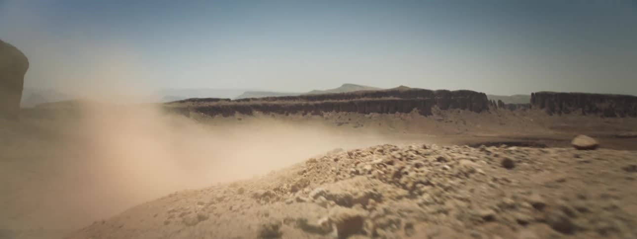 Person with a helmet and motocross clothing falling down a slope in the middle of the valley