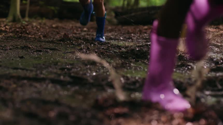 Three children run through the mud in the rain