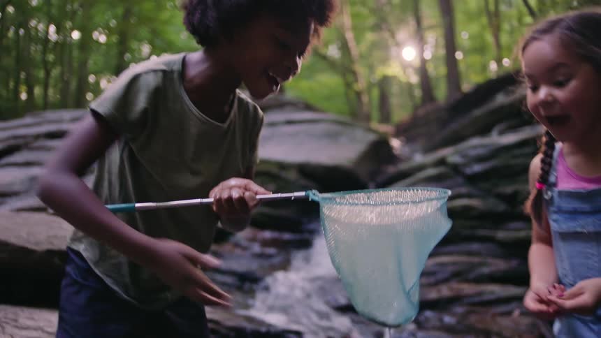 Two girls catch a fish from a stream
