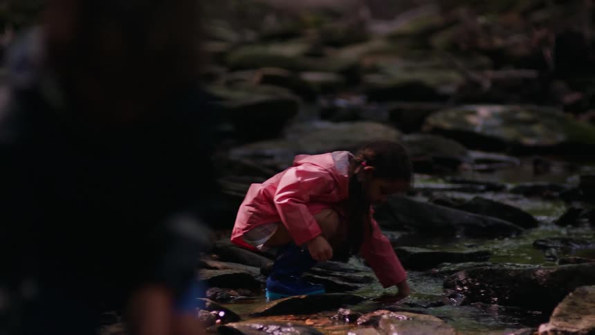 Two kids picking rocks from a small stream in the woods