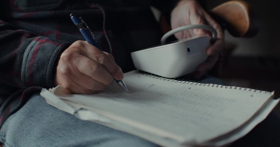An old man writes in a notebook