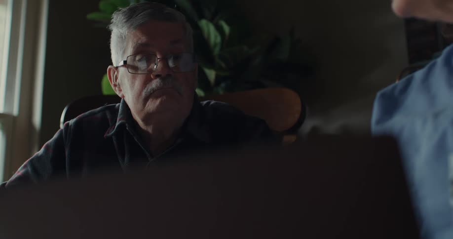 A man reading a document while talking to another person