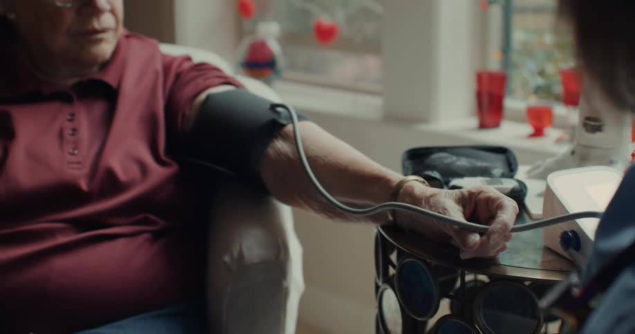 Elderly woman nervously gets her blood pressure taken by a nurse at home