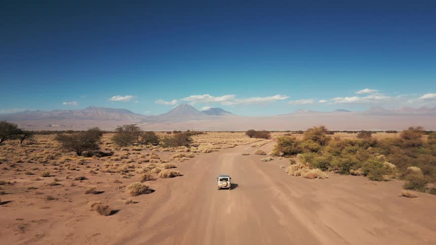 A truck drives on the dirt road through the desert