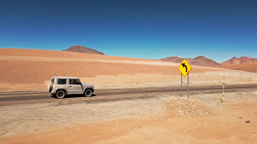 A vehicles is driving down the desert road