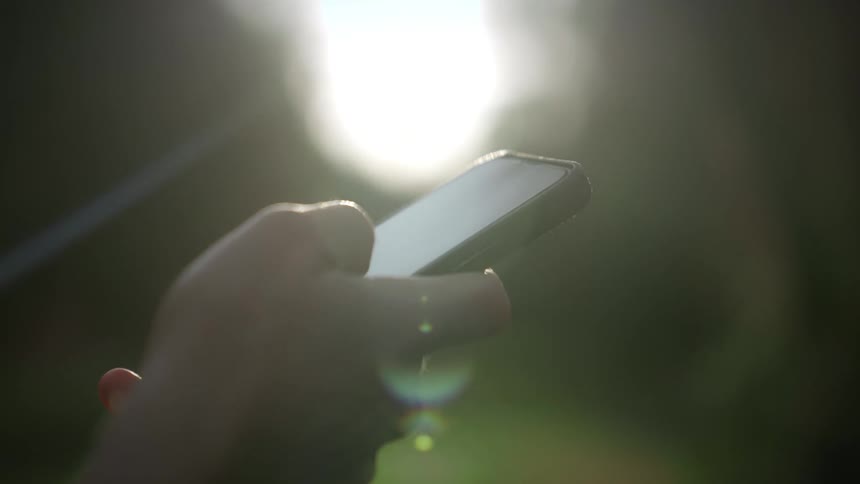 Closeup of a hand holding a smartphone illuminated by a soft light