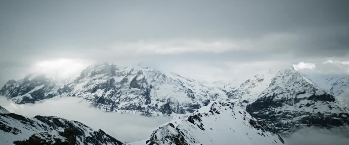 A large mountain range covered in snow under a cloudy sky