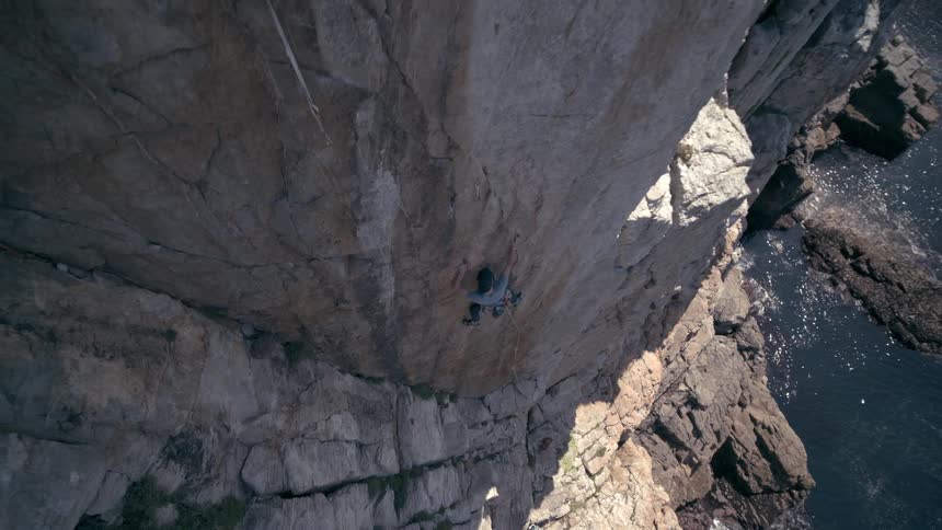 A man climbs a cliff on a coast