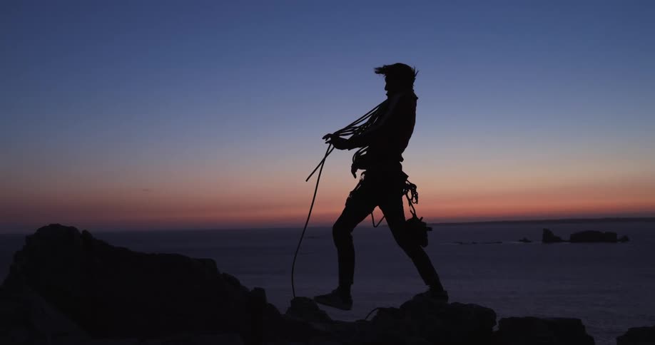 Silhouette of a person wearing climbing gear being pushed by the wind