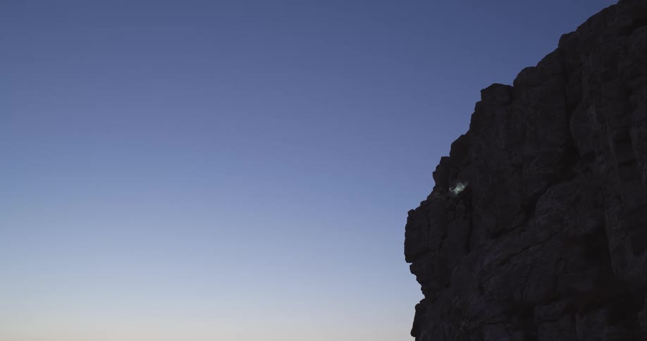 There is a hill with a faint light as the place is dark due to evening time
