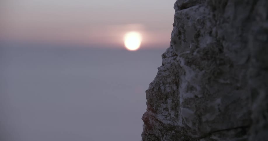 Rock wall next to the sea with morning sun on the horizon