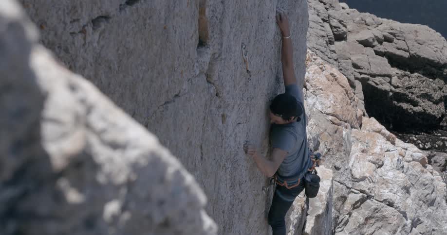 A man is climbing up a steep cliff