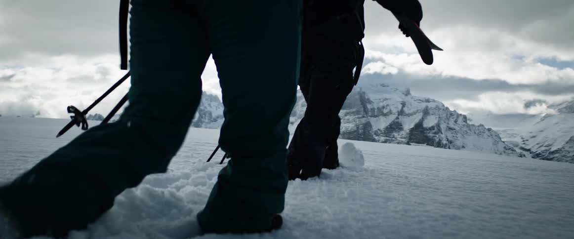 Two skiers walk across a snow covered valley