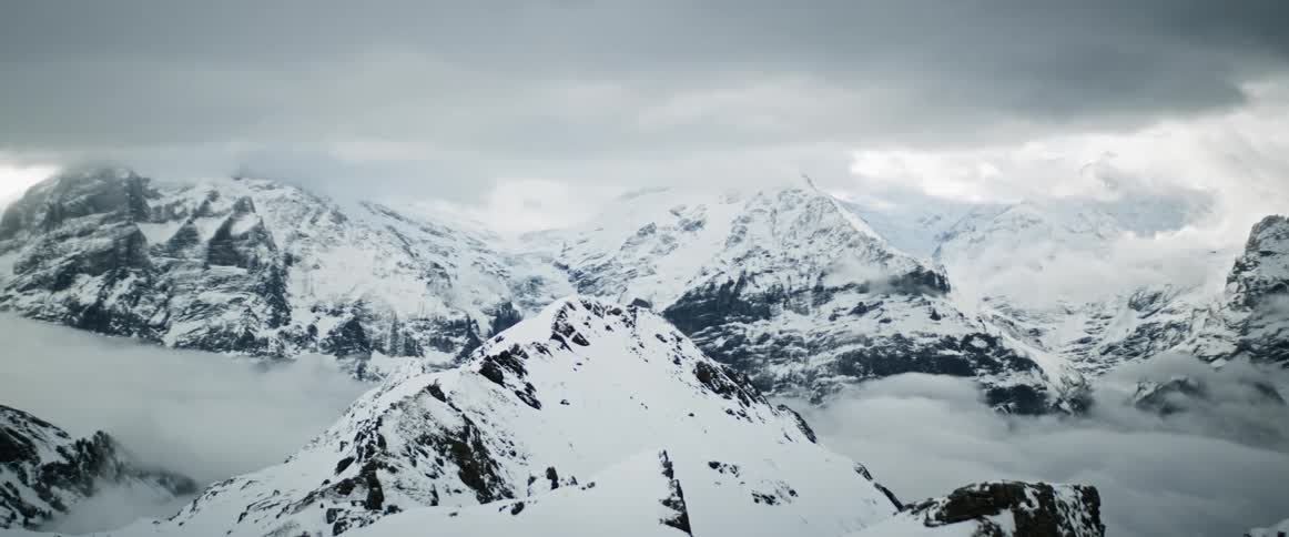 A large snow mountain range under a cloudy sky