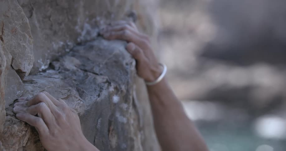 A man climbs a steep cliff on a coast