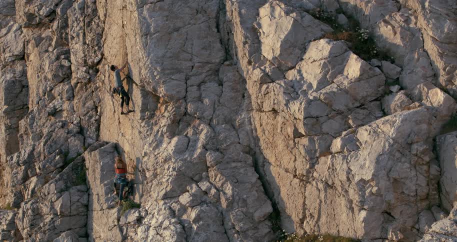 Two climbers ascend a rugged cliff