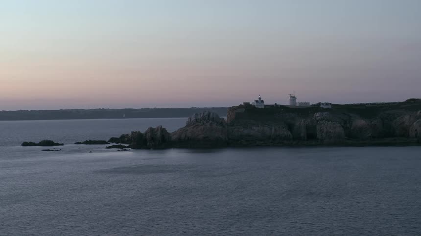 An island with some buildings in front of the sea