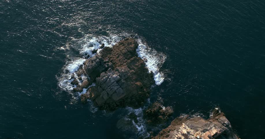 Aerial of a lonely rocky island emerging from the dark ocean waters