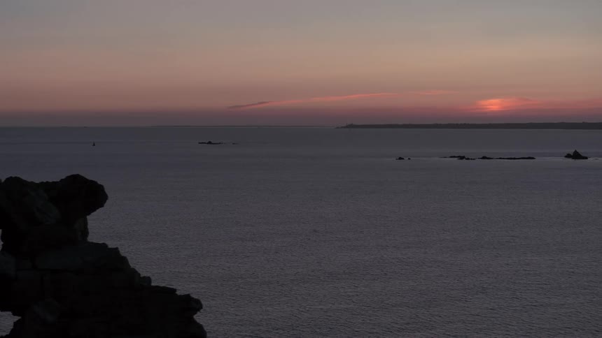 A rocky cliff area near the ocean during sunset