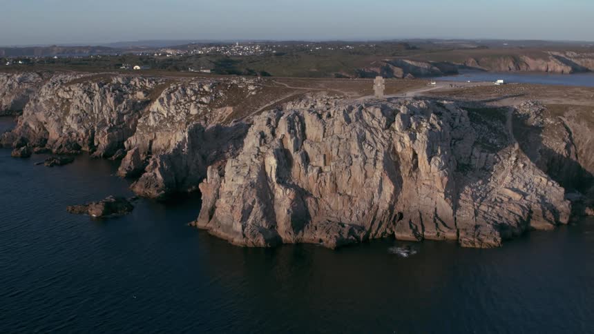 People are climbing up the cliff on the shore