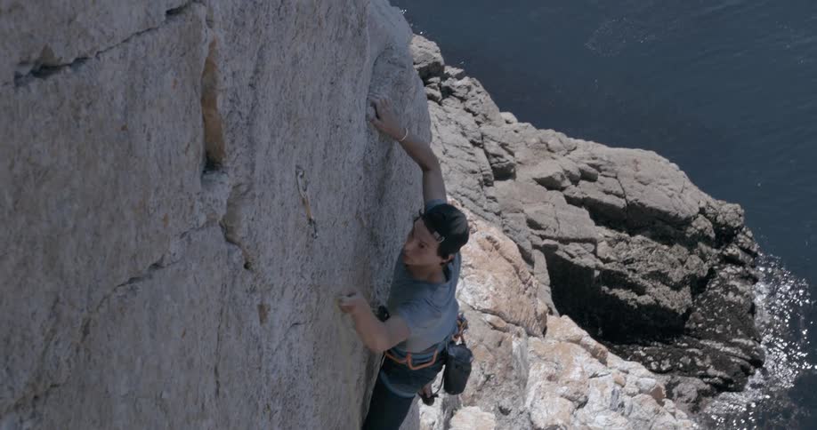 A man climbs a steep cliff on a coast