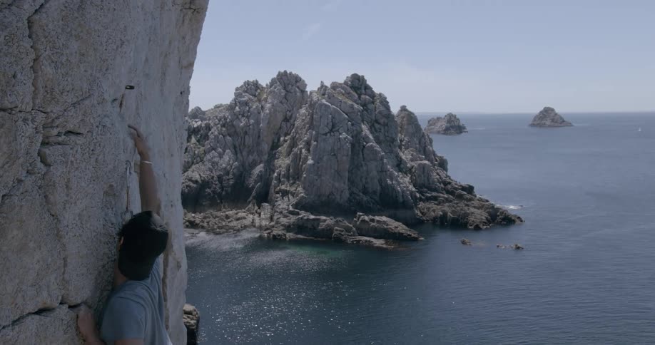 A man climbing a mountain near the ocean