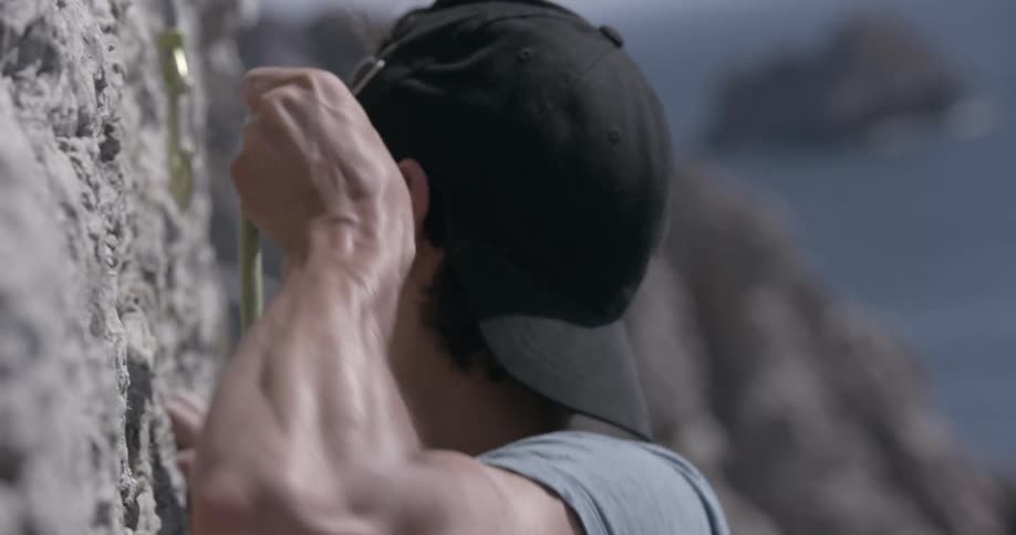 A young man climbs a cliff
